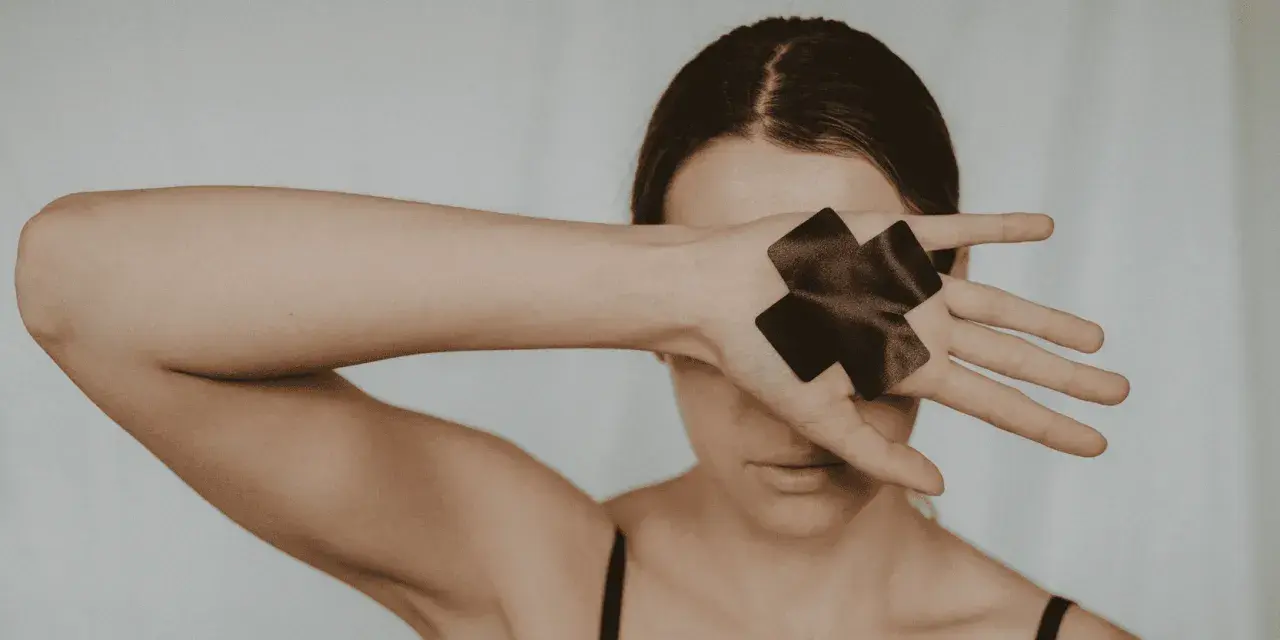 Femme cachant son visage avec sa main, ornée de deux croix noires.