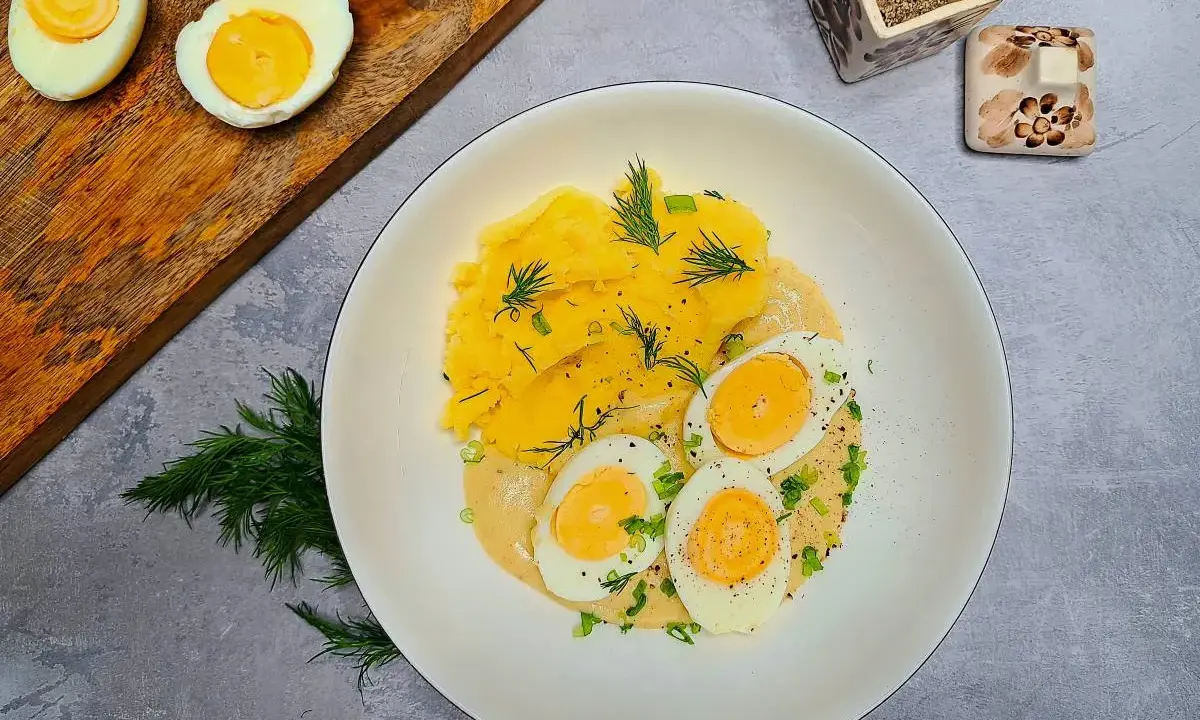 Pyszne jajka w sosie musztardowym z puree ziemniaczanym, udekorowane koperkiem i szczypiorkiem. Idealne na obiad.