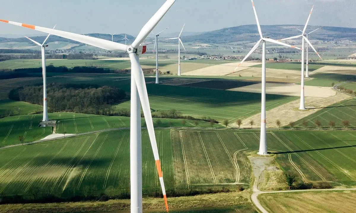 Weite Felder mit vielen weißen onshore Windkraftanlagen unter blauem Himmel.