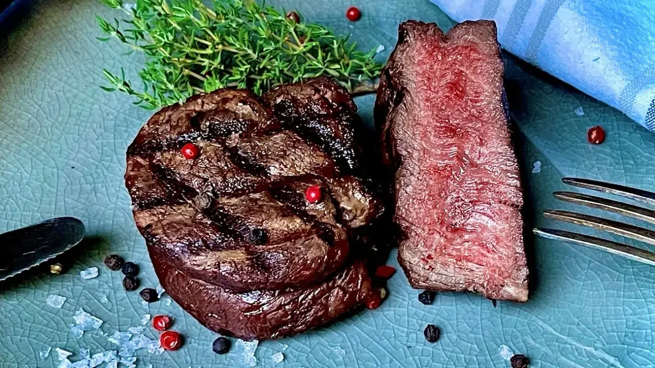 Perfekt gegrilltes Rinderfilet mit zarten rosa Kern, garniert mit Thymian, Pfeffer und grobem Salz. Ein Genuss für Fleischliebhaber!