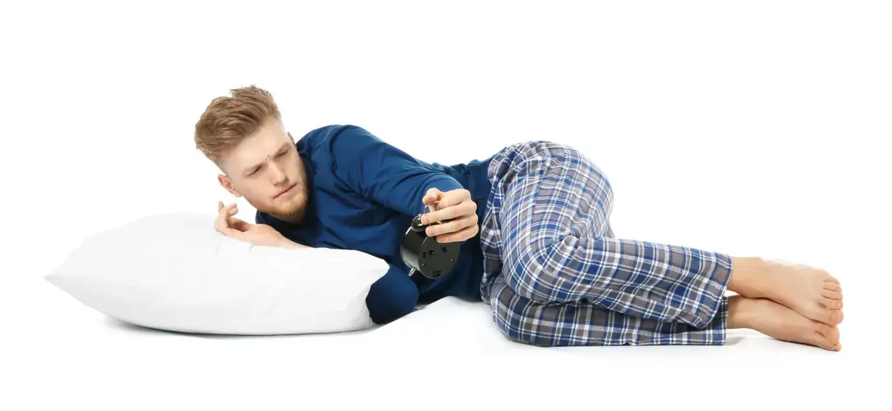 Mann liegt auf der Seite, weckt den Wecker. Die beste Schlafposition bei COPD kann helfen, besser zu atmen.