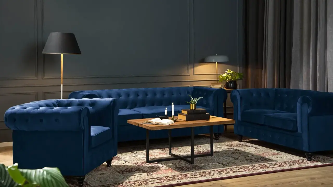 Lyxig blå soffa inspiration i ett elegant vardagsrum. En sammetsblå chesterfieldsoffa och fåtölj skapar en inbjudande sittgrupp.