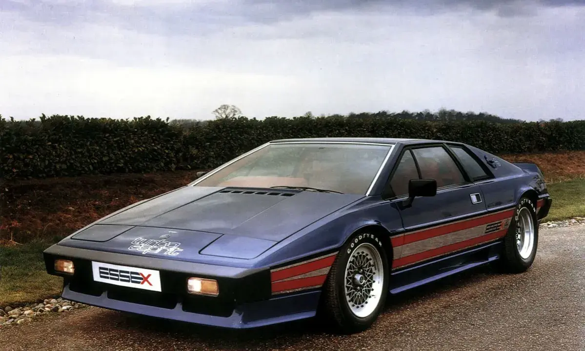 Niebieski Lotus Esprit Turbo Essex z czerwonymi pasami na boku, zaparkowany na drodze.