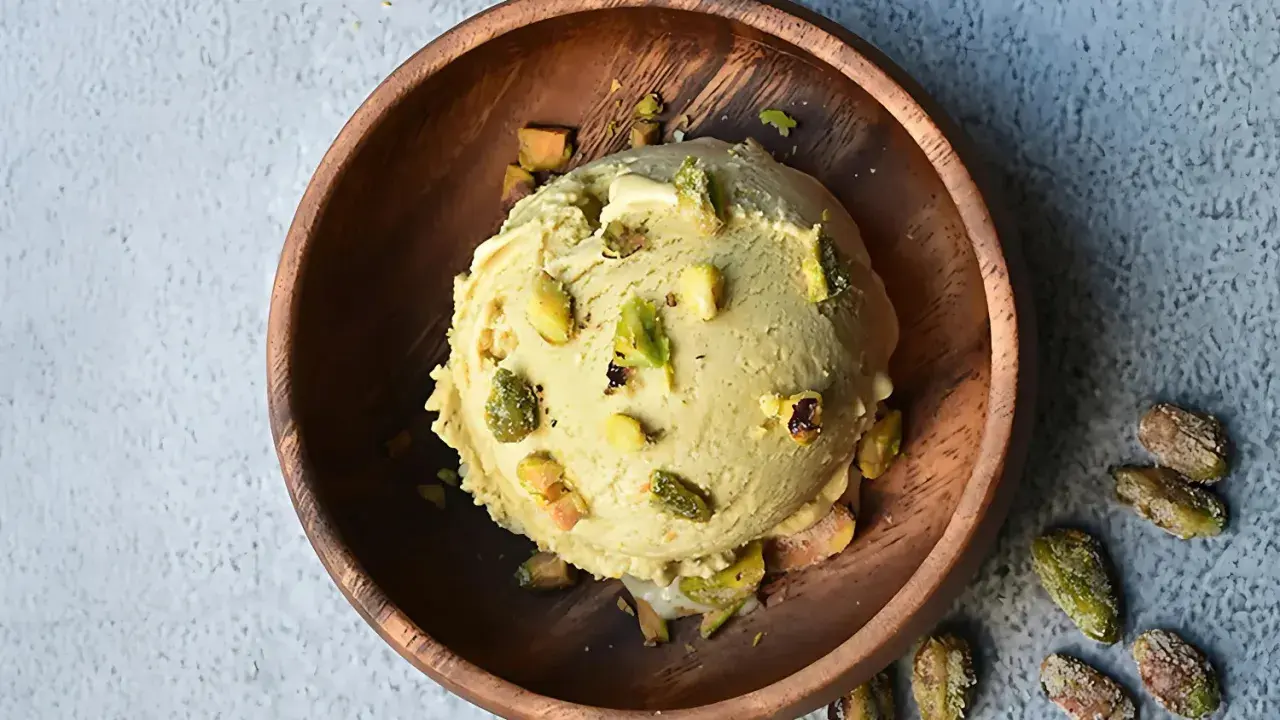 Cremoso helado de pistacho con trozos de pistacho en un cuenco de madera.