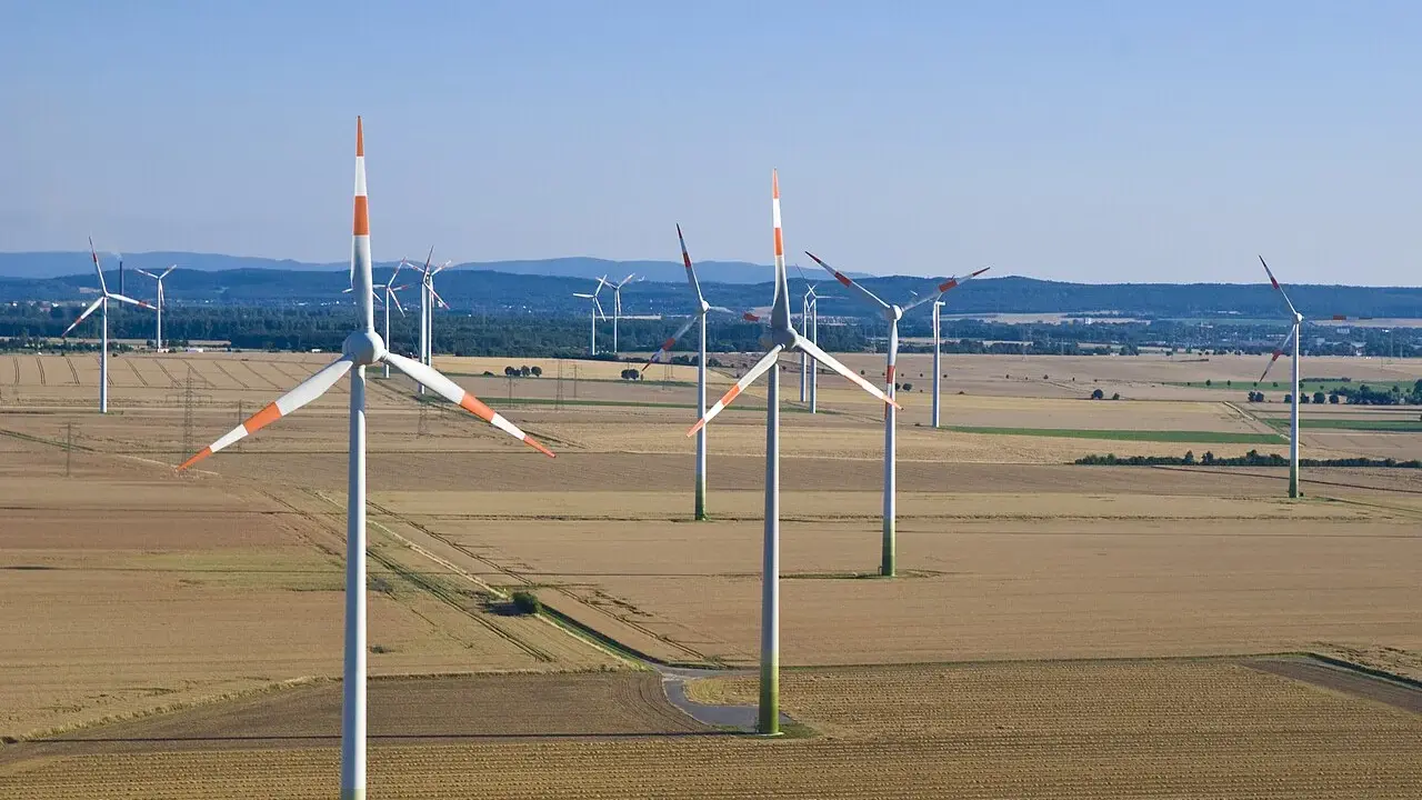 Großer onshore windpark in einer weiten Feldlandschaft unter blauem Himmel.