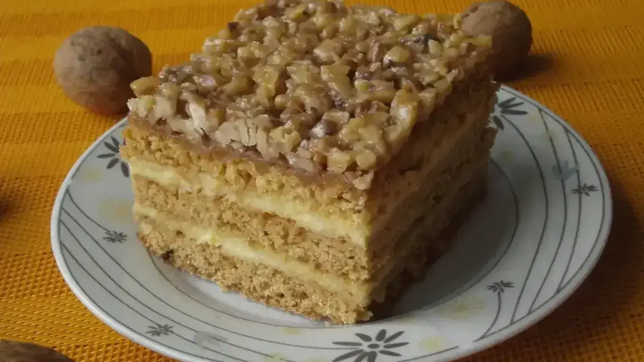 Pyszne ciasto miodowe z orzechami, jedno z 10 najlepszych ciast, na talerzyku z orzechami w tle.