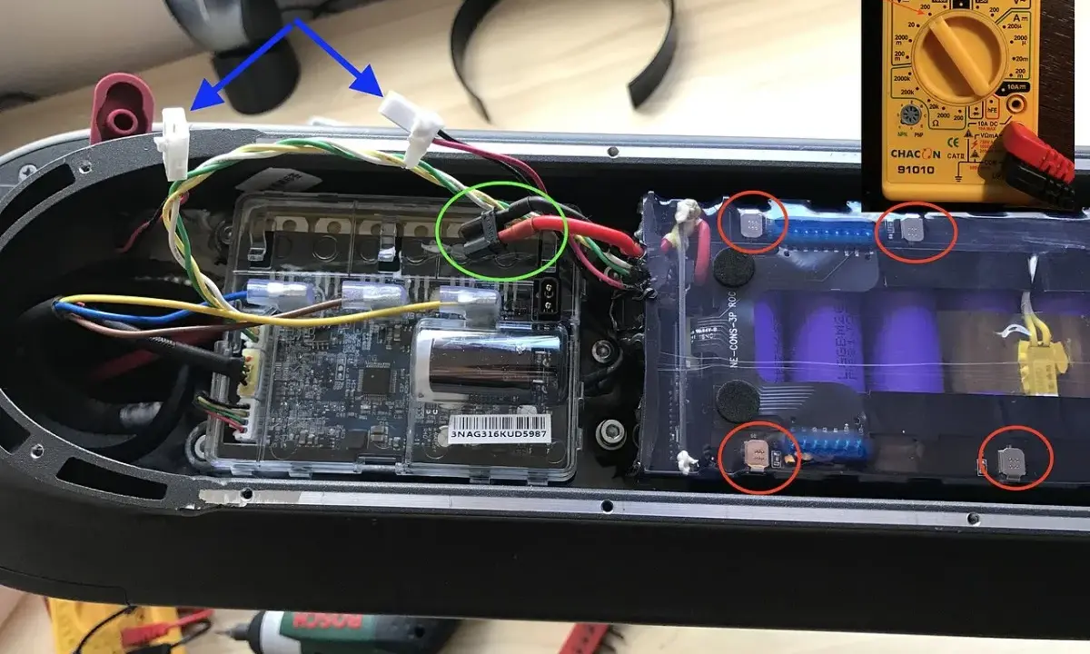 Le fusible de la trottinette électrique est ici, près des connexions de la batterie. Un multimètre est visible.