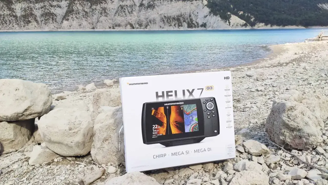 Boîte d'un Humminbird HELIX 7 G3 avec écran affichant des images side imaging, posée sur des rochers au bord d'un lac.