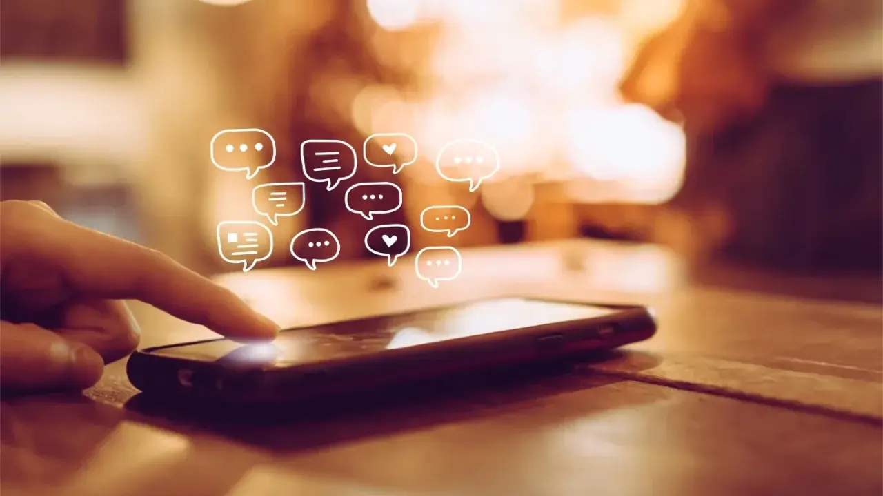 Palec dotyka ekranu telefonu, a nad nim pojawiają się dymki czatu. Dowiedz się, jak odzyskać wiadomości z kosza w telefonie.