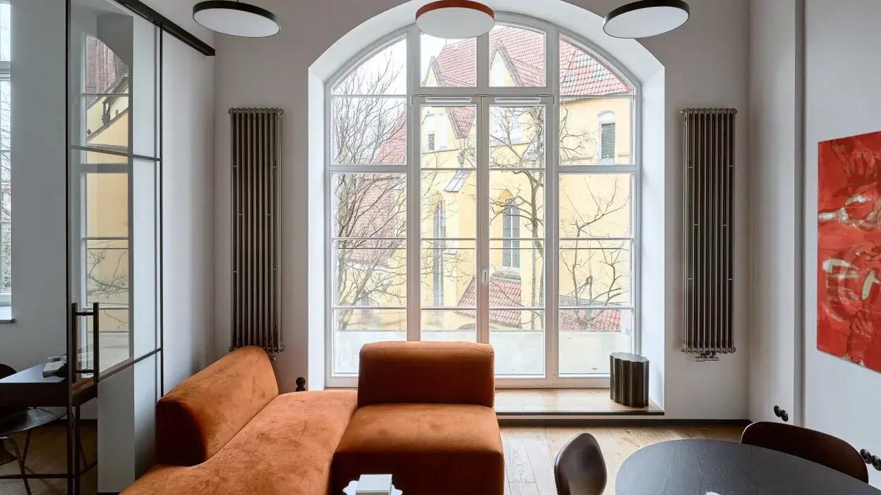 Nowoczesny salon z pomarańczową kanapą, czarnym stolikiem i obrazem. Jakie dodatki podkreślają styl?