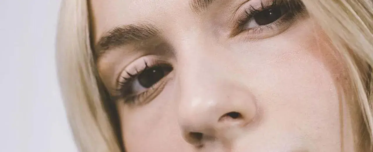 Primer plano de un ojo y nariz de mujer rubia. Consejos sobre como disimular las bolsas de los ojos.