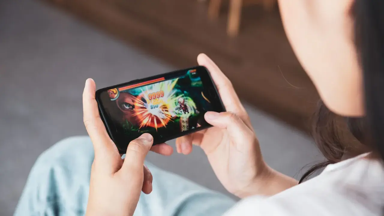 Osoba gra w ekscytujące gry multiplayer na telefonie, walcząc z potężnym przeciwnikiem.