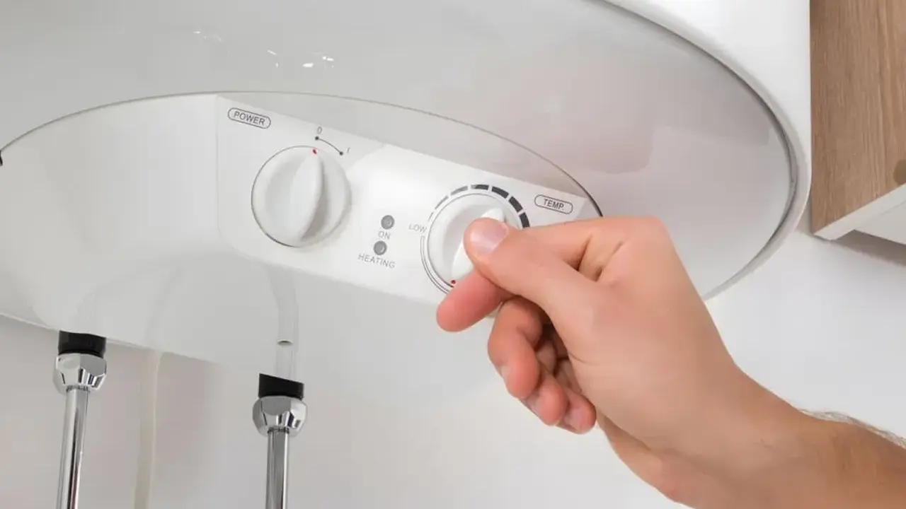 Mano ajustando el termostato de un termo eléctrico. Averigua cuanto dura un termo eléctrico y optimiza su uso.