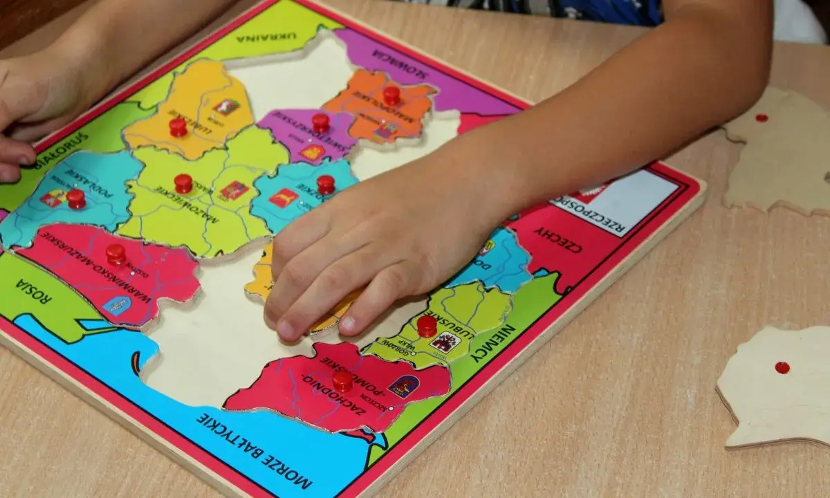 Dziecko układa puzzle z mapą Polski, ucząc się regionów. To świetne gry dydaktyczne w przedszkolu.