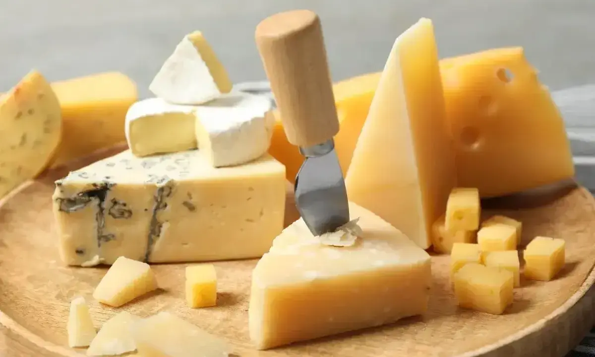 Deska serów: pleśniowy, camembert i twarde sery, w tym ser sałatkowy pokrojony w kostkę.
