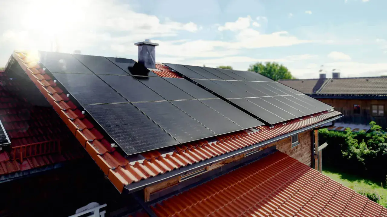Solceller tillverkning på ett tegeltak. Solen skiner på panelerna som fångar upp energin.