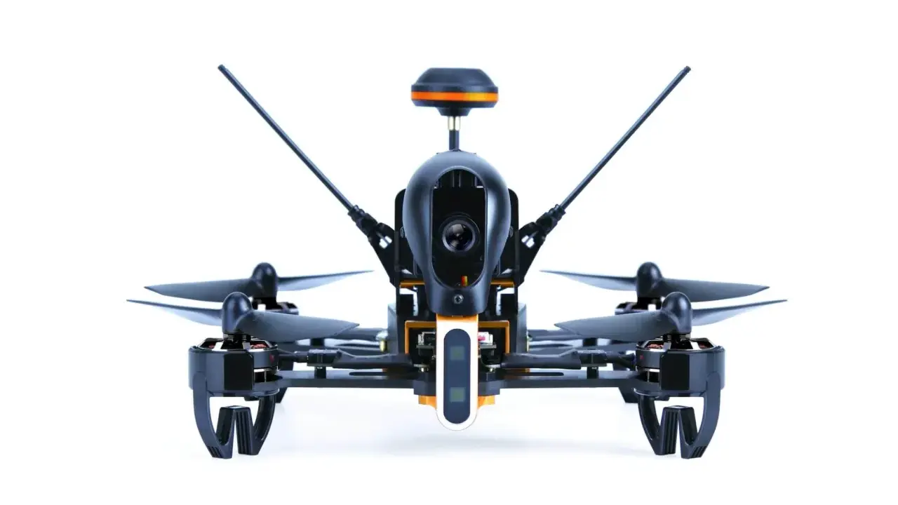 Ich sehe aus der **first person view** auf einen schwarzen Quadrocopter mit orangefarbenen Akzenten. Seine Kamera ist bereit für den Flug.