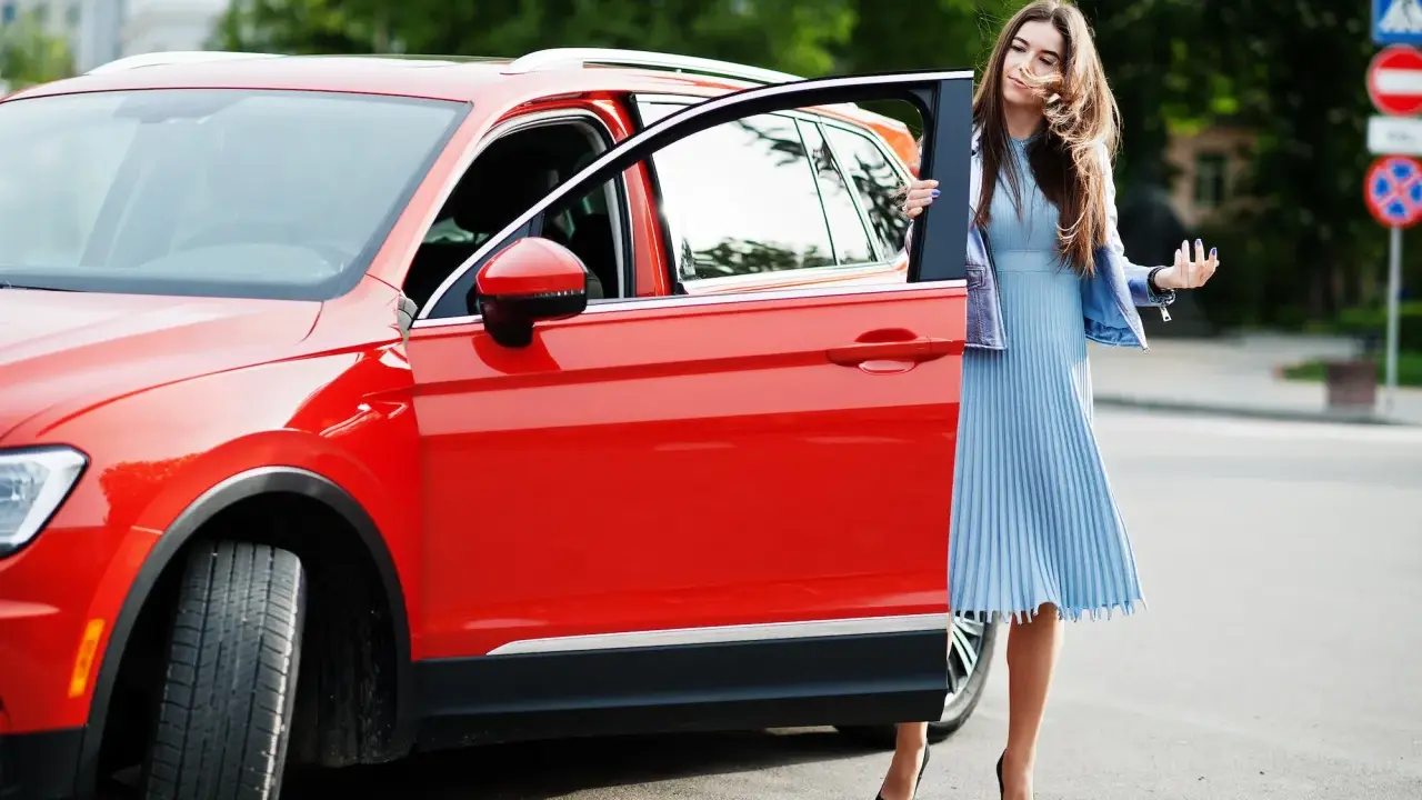Mujer elegante sale de un monovolumen o SUV rojo brillante.