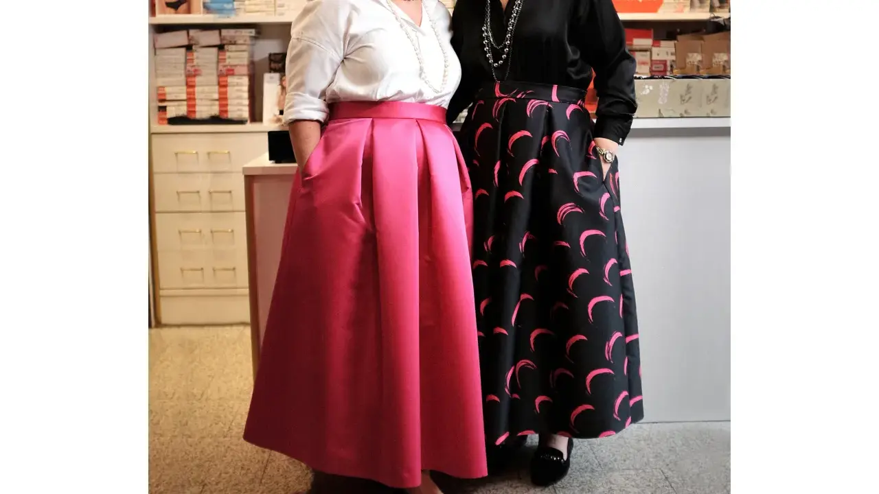 Due donne mostrano diversi tipi di gonne: una rosa a pieghe e una nera con stampa a mezzelune rosa.