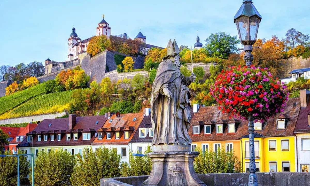 Statua sul ponte di Würzburg, con la fortezza in cima alla collina e i vigneti. Perfetto per un itinerario di 7 giorni sulla Romantische Straße.
