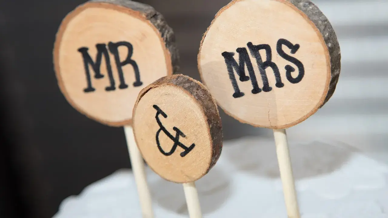 Drewniane krążki z napisami MR i MRS, symbolizujące Parę Młodą, ozdabiają tort.
