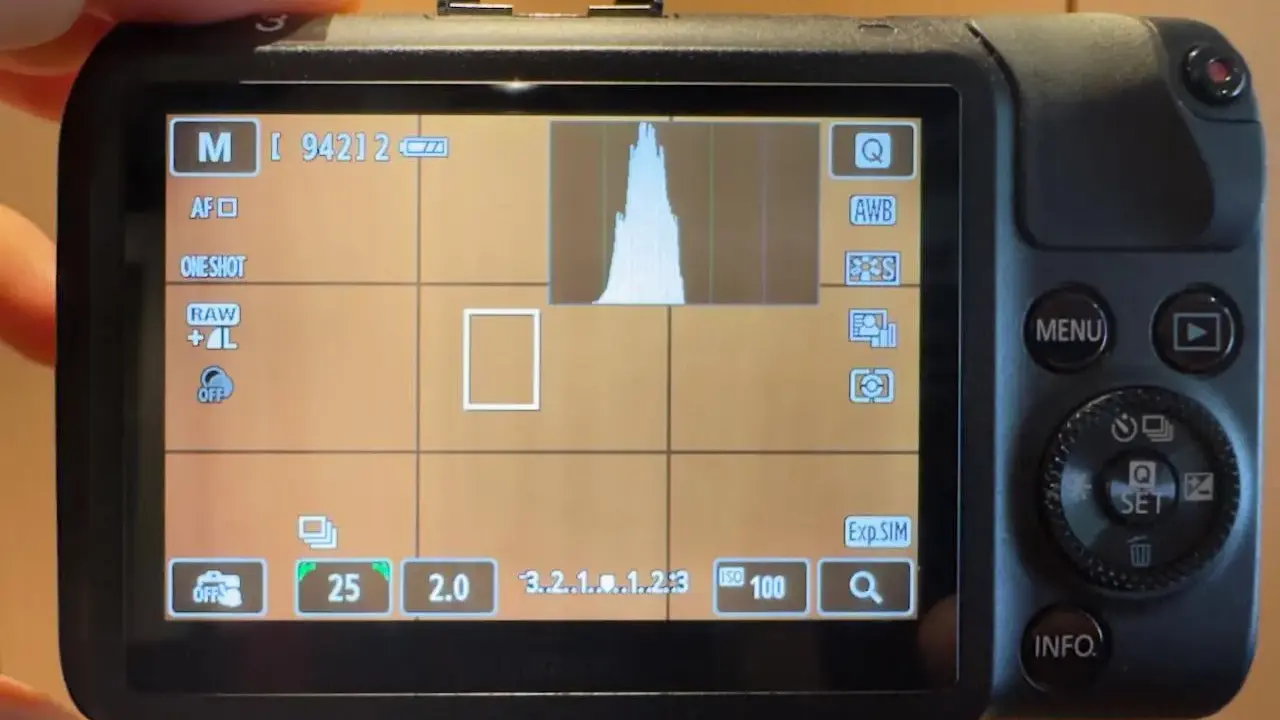Schermo di una fotocamera **Canon M** in modalità manuale, con istogramma e impostazioni visibili.