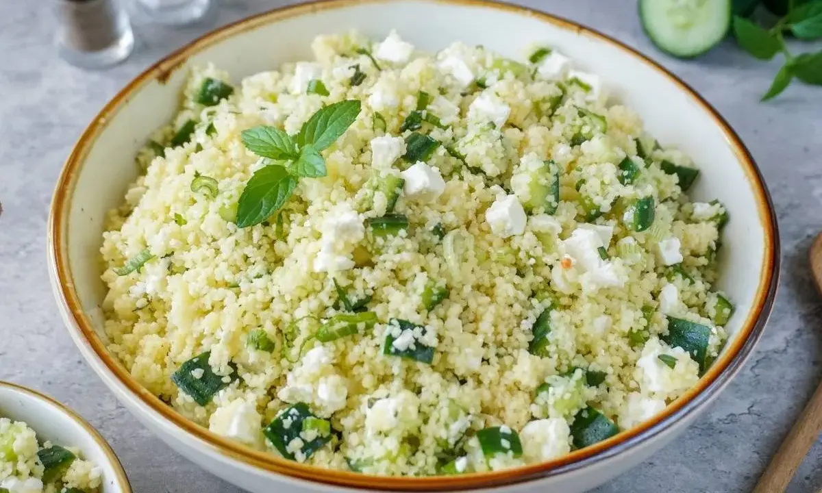 Frischer Couscous Salat mit Feta, Gurken und Minze, garniert mit einer Minzblatt.
