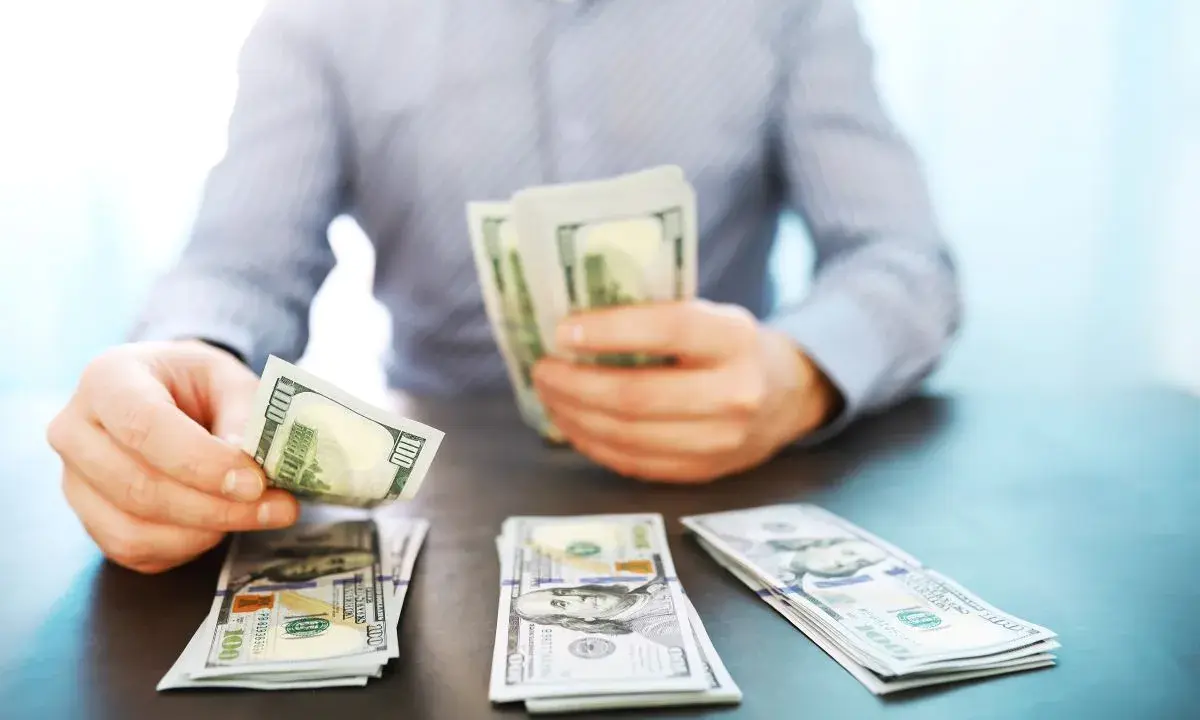 Mężczyzna liczy banknoty 100-dolarowe, symbolizujące dobrze płatne zawody i sukces finansowy.