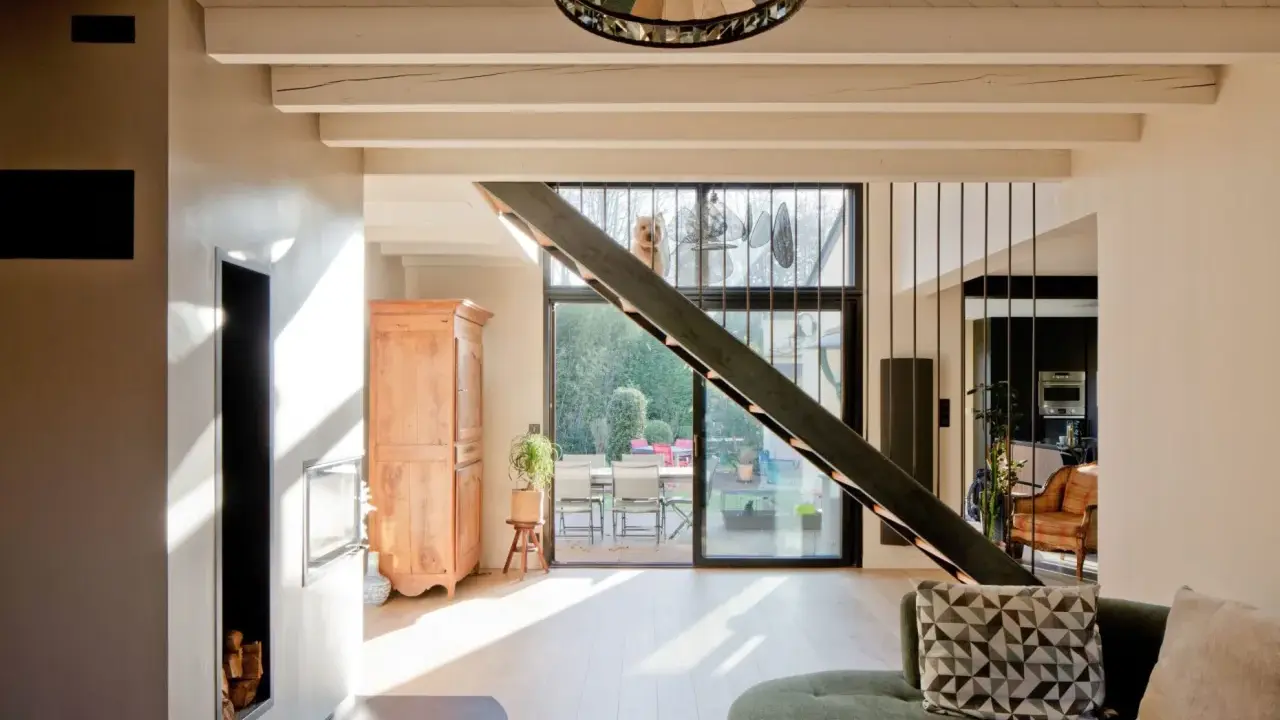 Rénovation d'une maison année 70 : avant, un style désuet ; après, un espace lumineux avec escalier moderne, poêle design et vue sur jardin.