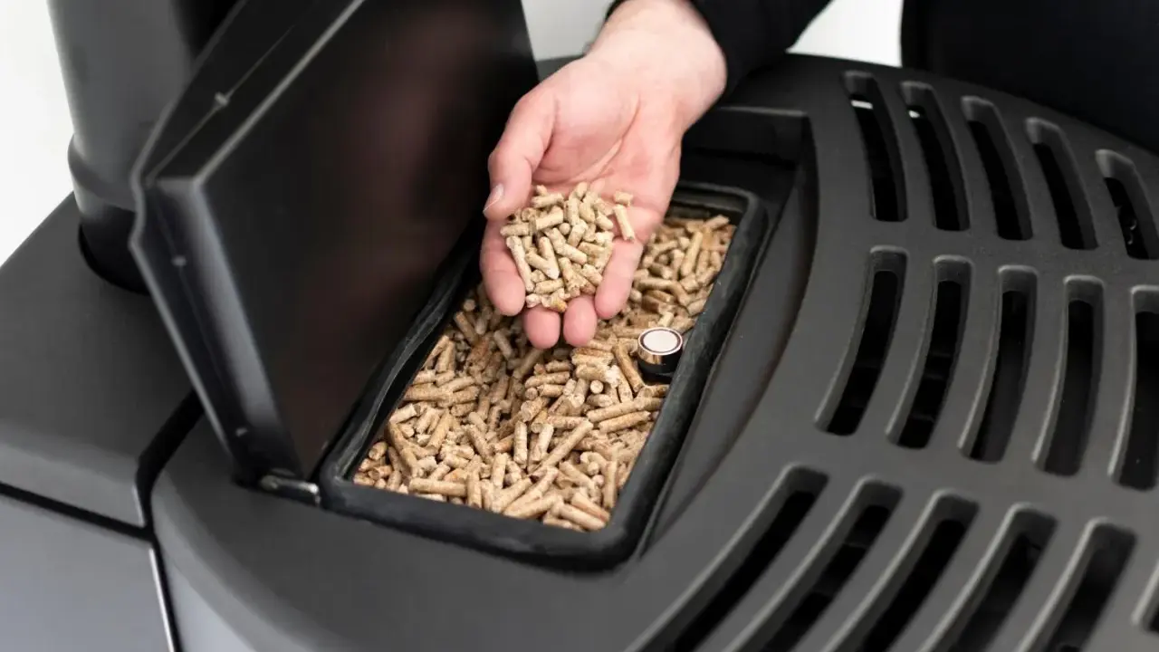 Mano sosteniendo **que es el pellet**, combustible para estufas, listo para ser añadido.