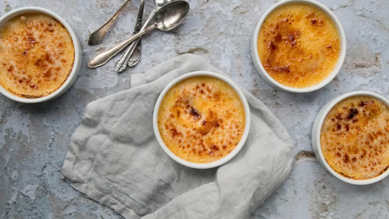 Quatre crèmes brûlées dorées, prêtes à être dégustées. La croûte caramélisée de cette crème catalane invite à la gourmandise.