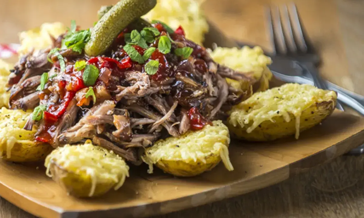 Pulled pork med en härlig sås till, serverad med ugnsbakade potatishalvor gratinerade med ost och en dillkvist.
