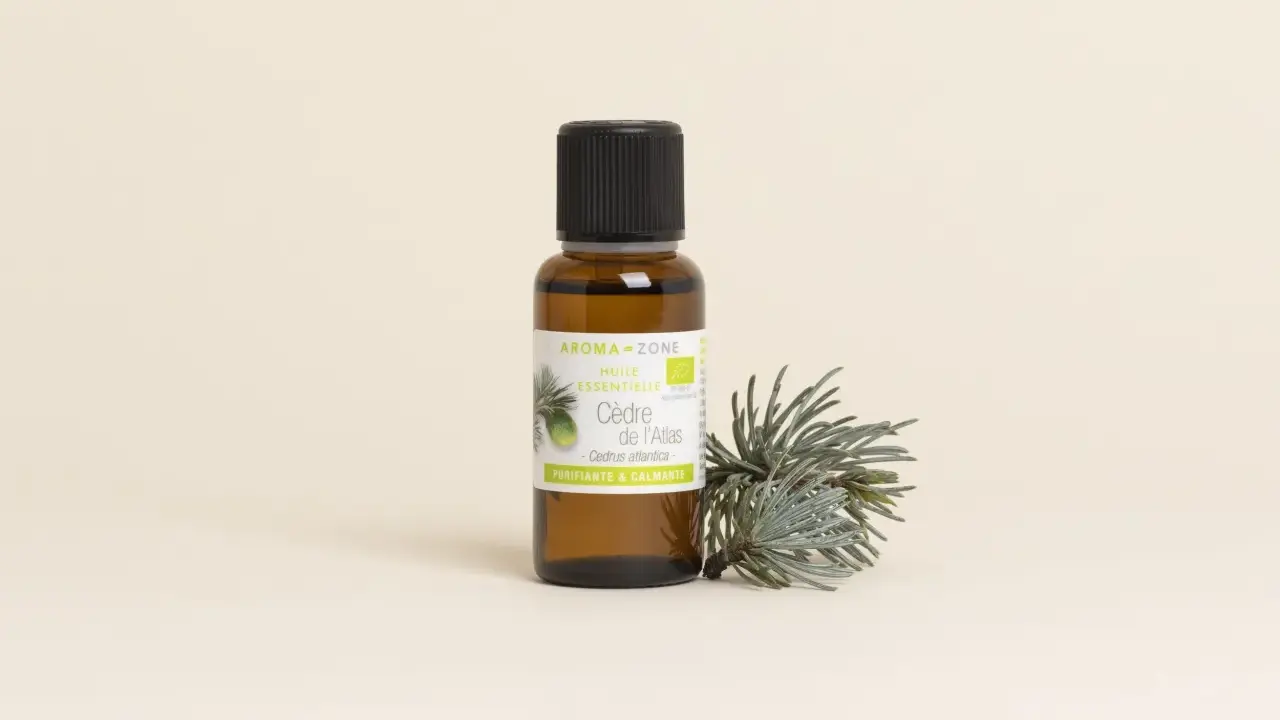 Flacon d'huile essentielle de cèdre de l'Atlas, aux vertus purifiantes et calmantes, posé à côté d'une branche de cèdre.