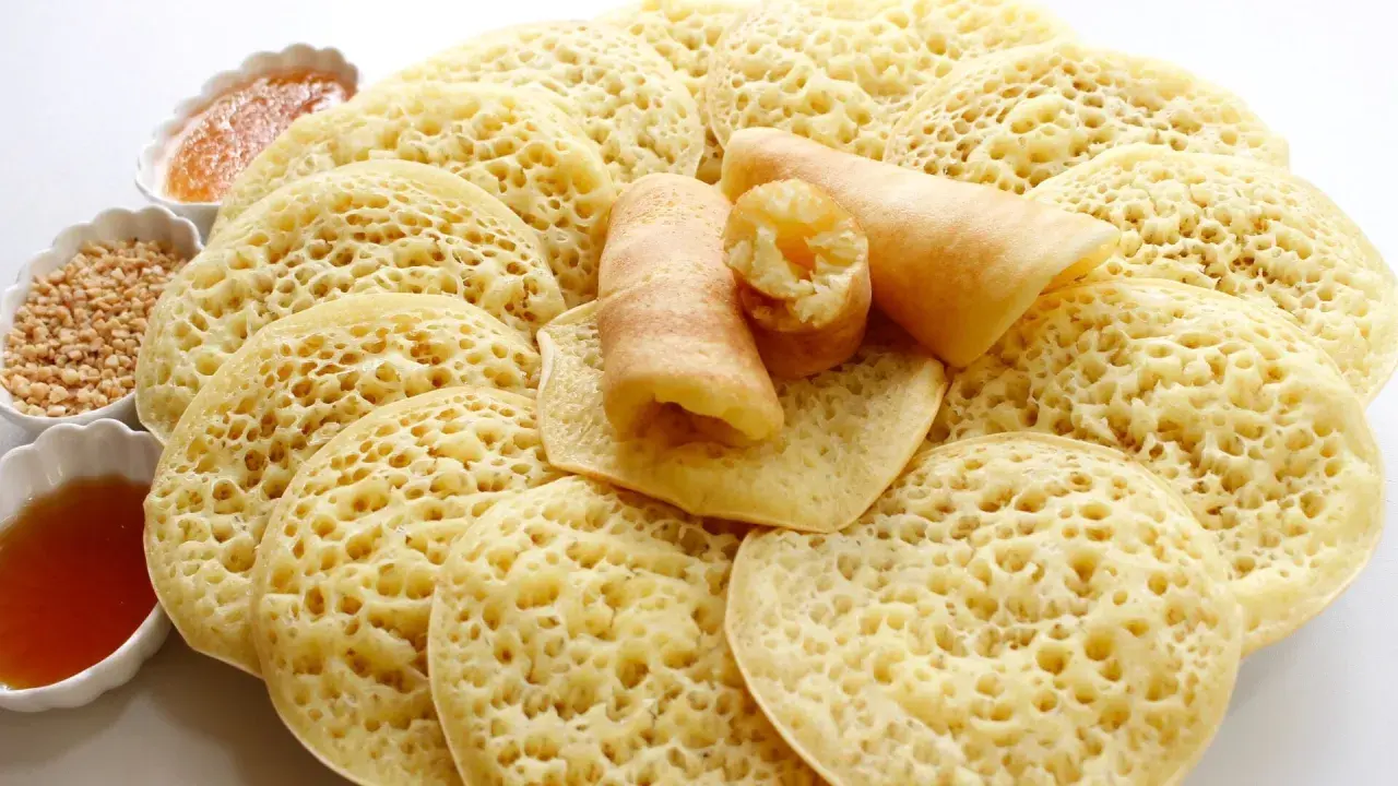 Assiette de crêpes mille trous, garnies de miel et de cacahuètes concassées. Un délice à déguster !