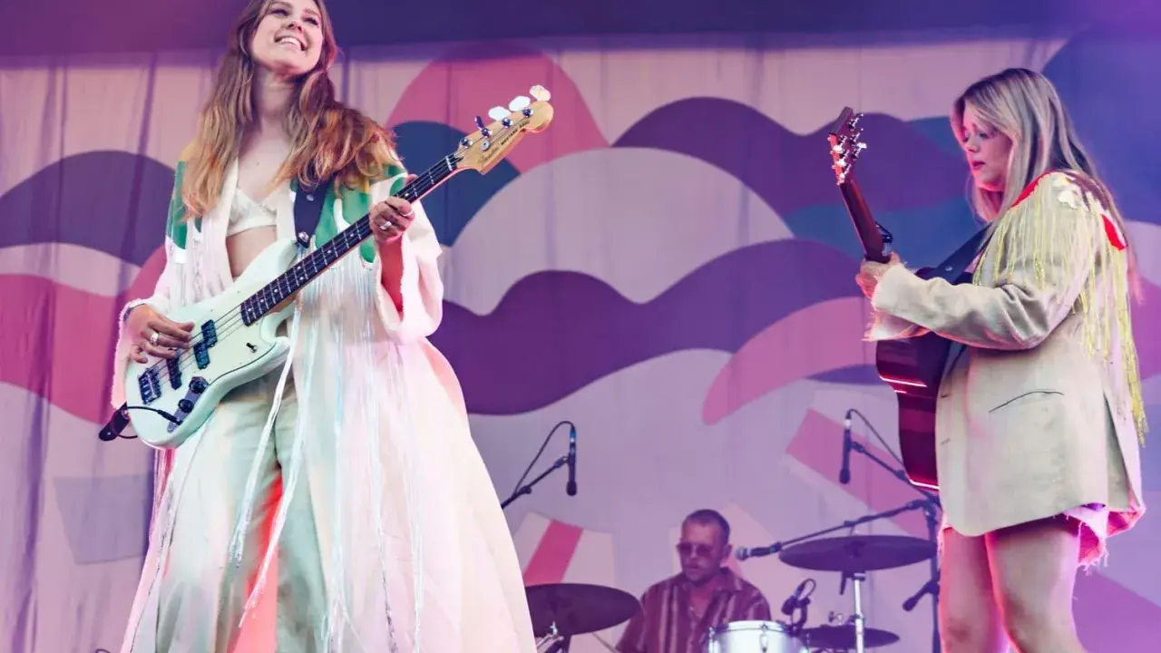 Kvinnlig basist och gitarrist uppträder på en konsert. Bakom dem sitter en trummis. En **first aid kit konsert** kan vara bra att ha nära till hands.