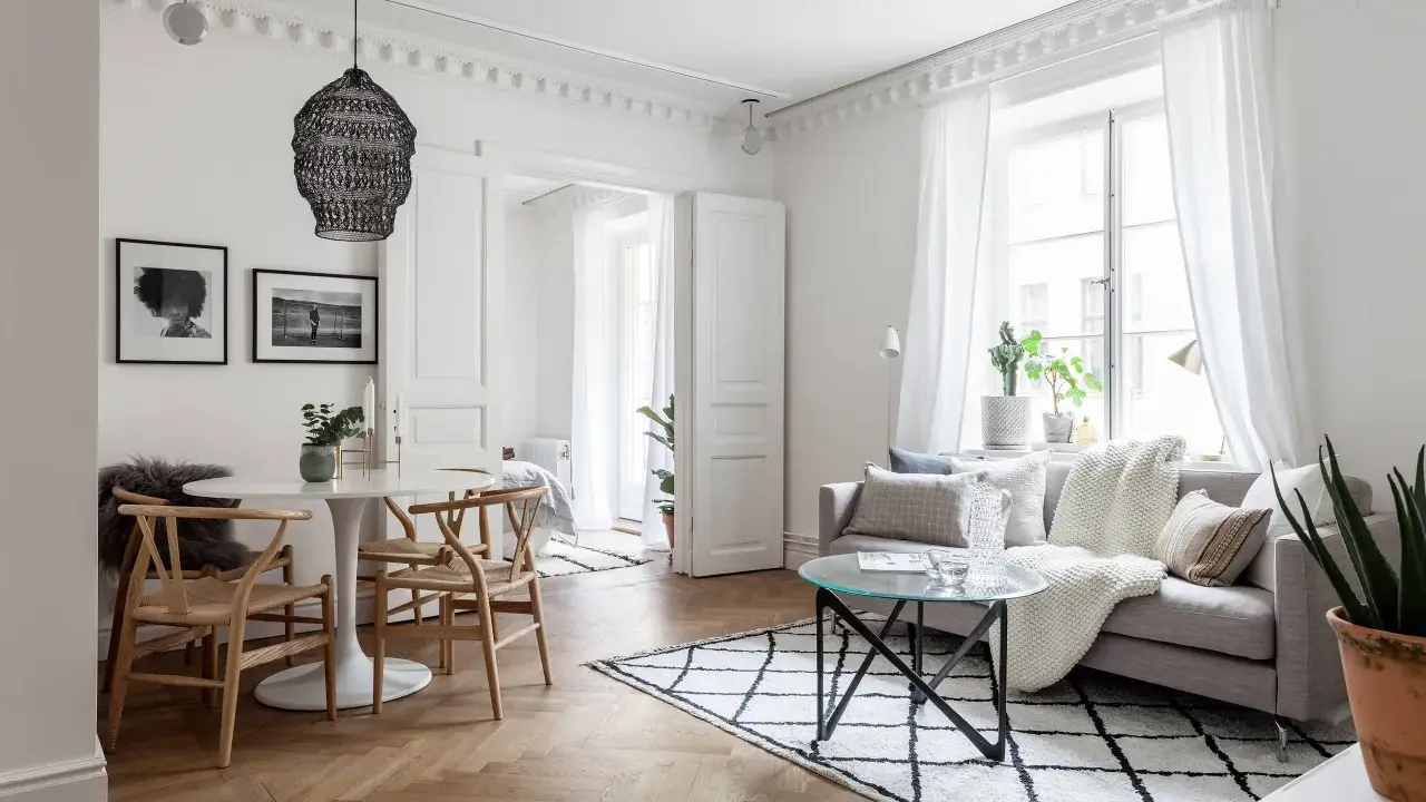Ljust och luftigt vardagsrum med matbord och inspiration från skandinavisk design. En rund vit matplats med trästolar möter en soffgrupp med mysiga textilier.