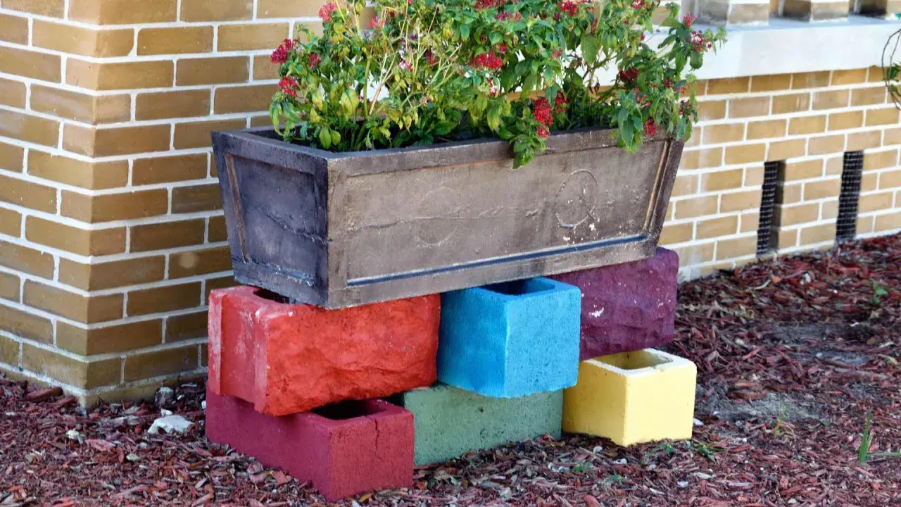 Un bac à fleurs sur des blocs de béton colorés, une idée de **diy jardin** pour rehausser vos plantes.