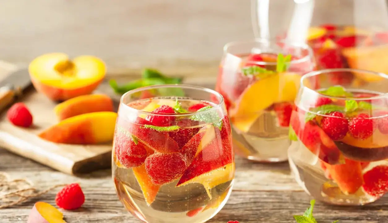 Délicieuse sangria blanche recette avec pêches, framboises et menthe fraîche. Parfait pour se rafraîchir !
