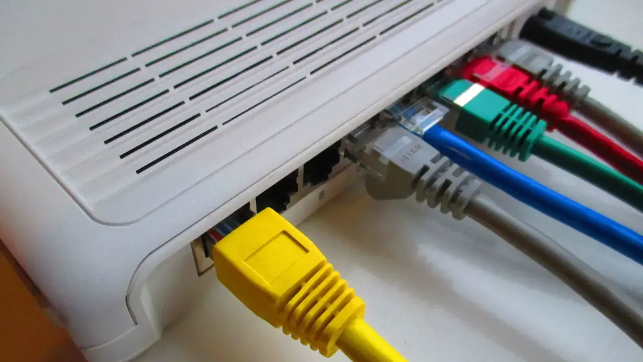 Router z podłączonymi kolorowymi kablami sieciowymi.
