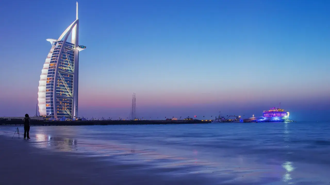 Wieżowiec Burdż al-Arab i plaża w Dubaju o zmierzchu.