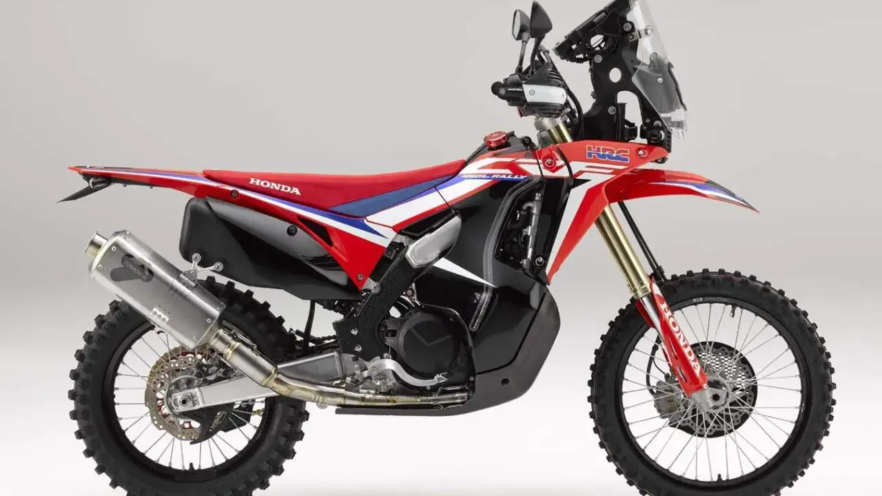 Czerwono-biały motocykl Honda CRF 450 Rally z czarnymi akcentami, gotowy na rajdowe wyzwania.