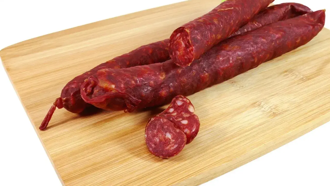 Trzy kawałki pikantnego chorizo na desce. Zastanawiasz się chorizo co to? To aromatyczna, suszona kiełbasa.