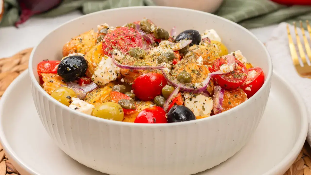 Schüssel mit einem frischen griechischen Kartoffelsalat, garniert mit Oliven, Tomaten, Kapern und Feta.