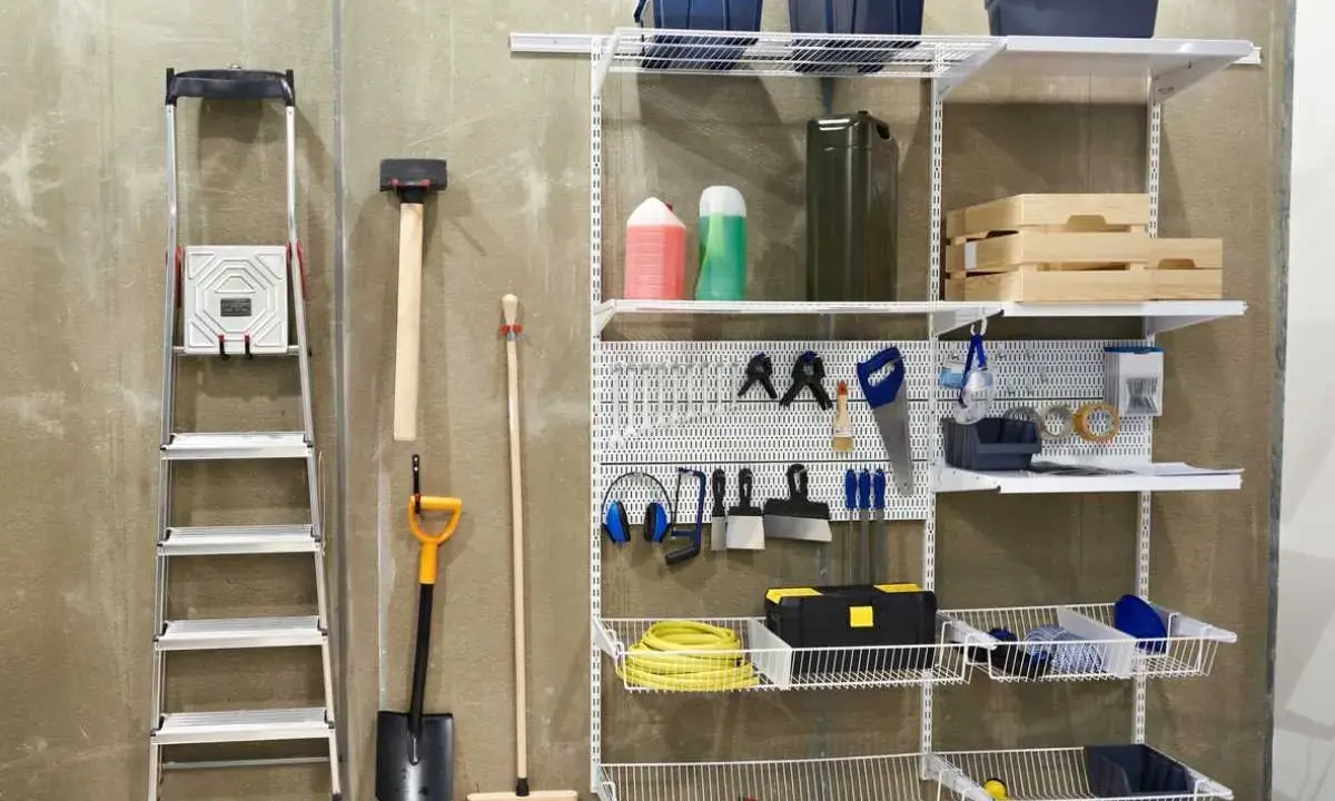Estanterías y herramientas para saber como ordenar un garaje: escalera, pala, escoba, martillo, caja de herramientas, cubos y más.