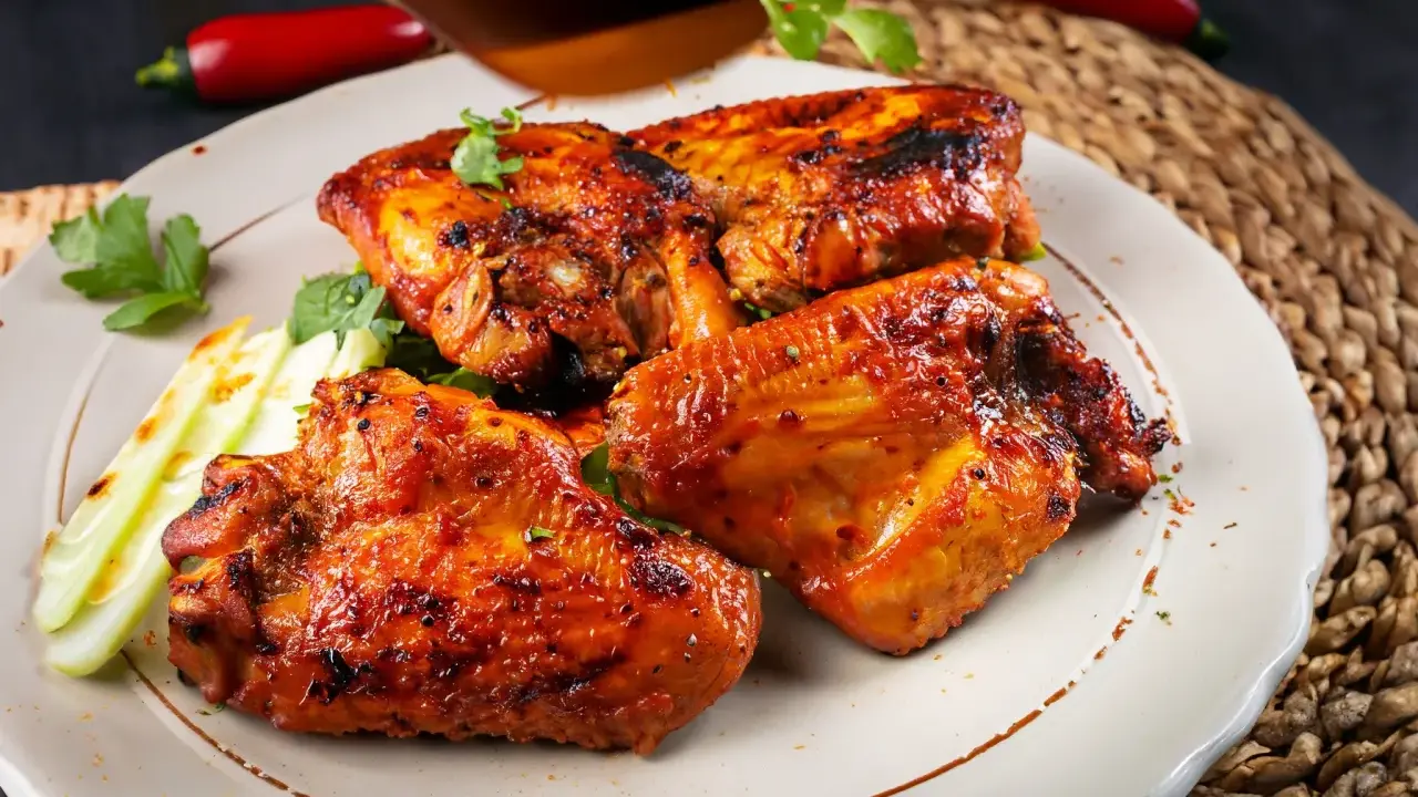 Saftige Hähnchenflügel, perfekt gegrillt, ein köstliches pollo fino rezept. Garniert mit frischer Petersilie und knackigem Sellerie.