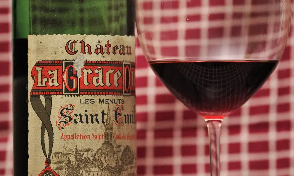 Ein Glas Rotwein neben einer Flasche Château La Grace Dieu, ein Saint-Émilion Grand Cru.