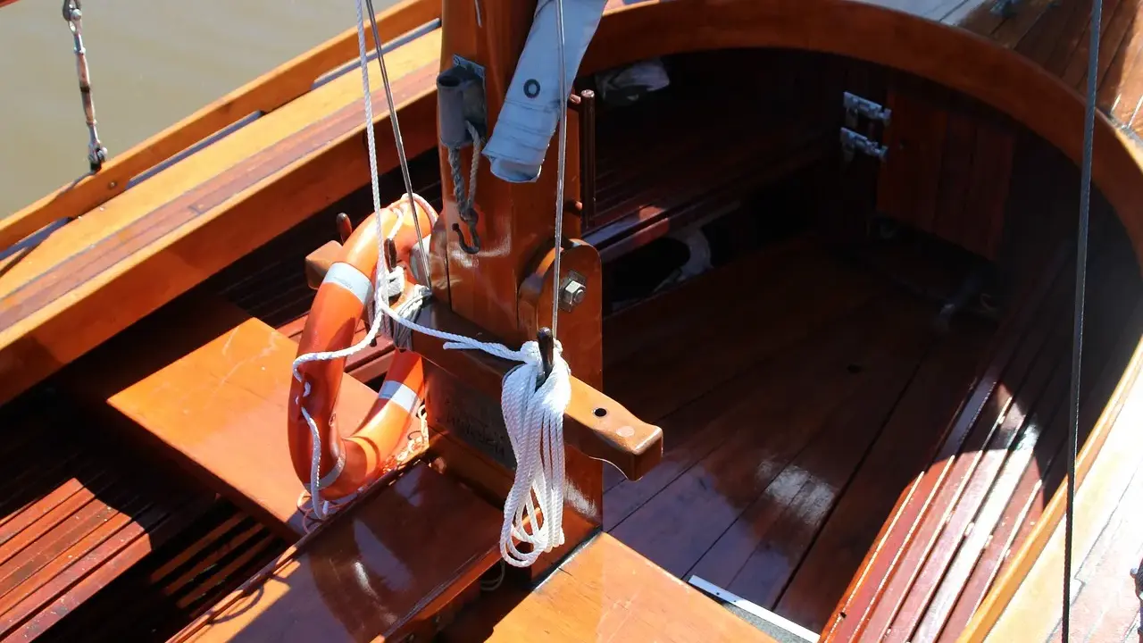 Le bois de bateau verni brille au soleil. Une bouée orange est accrochée, prête pour l'aventure.