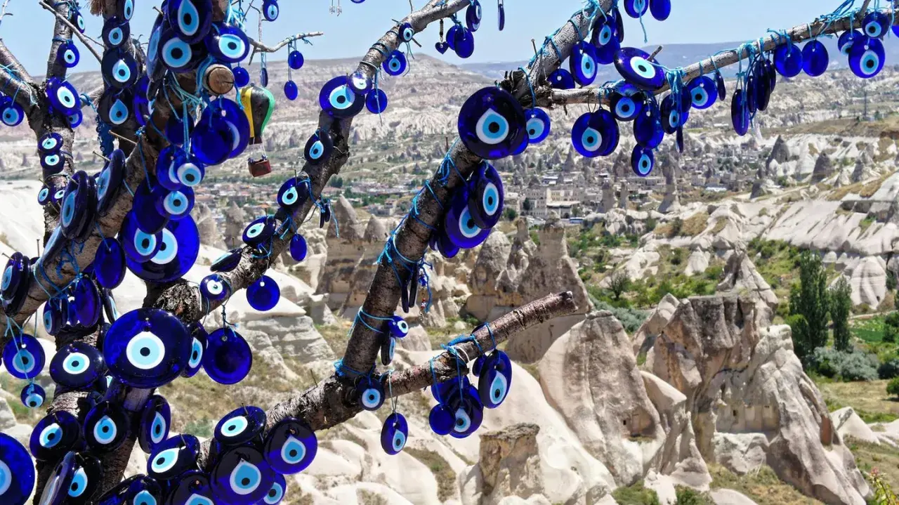 Ein Baum voller blauer Glasaugen, die wie ein arabisches Auge vor der Felslandschaft von Kappadokien schützen.