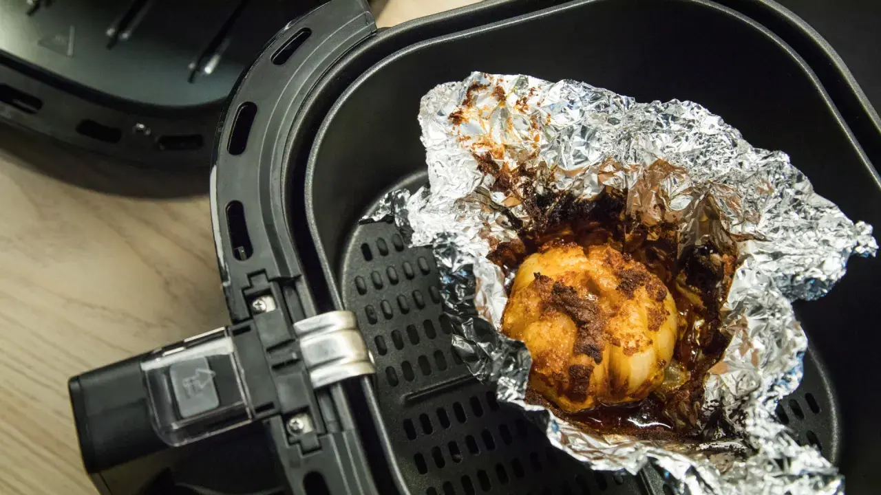 Ein gebackener Knoblauch in Alufolie in einem Airfryer. Ist Airfryer gesund? Ja, mit wenig Öl.