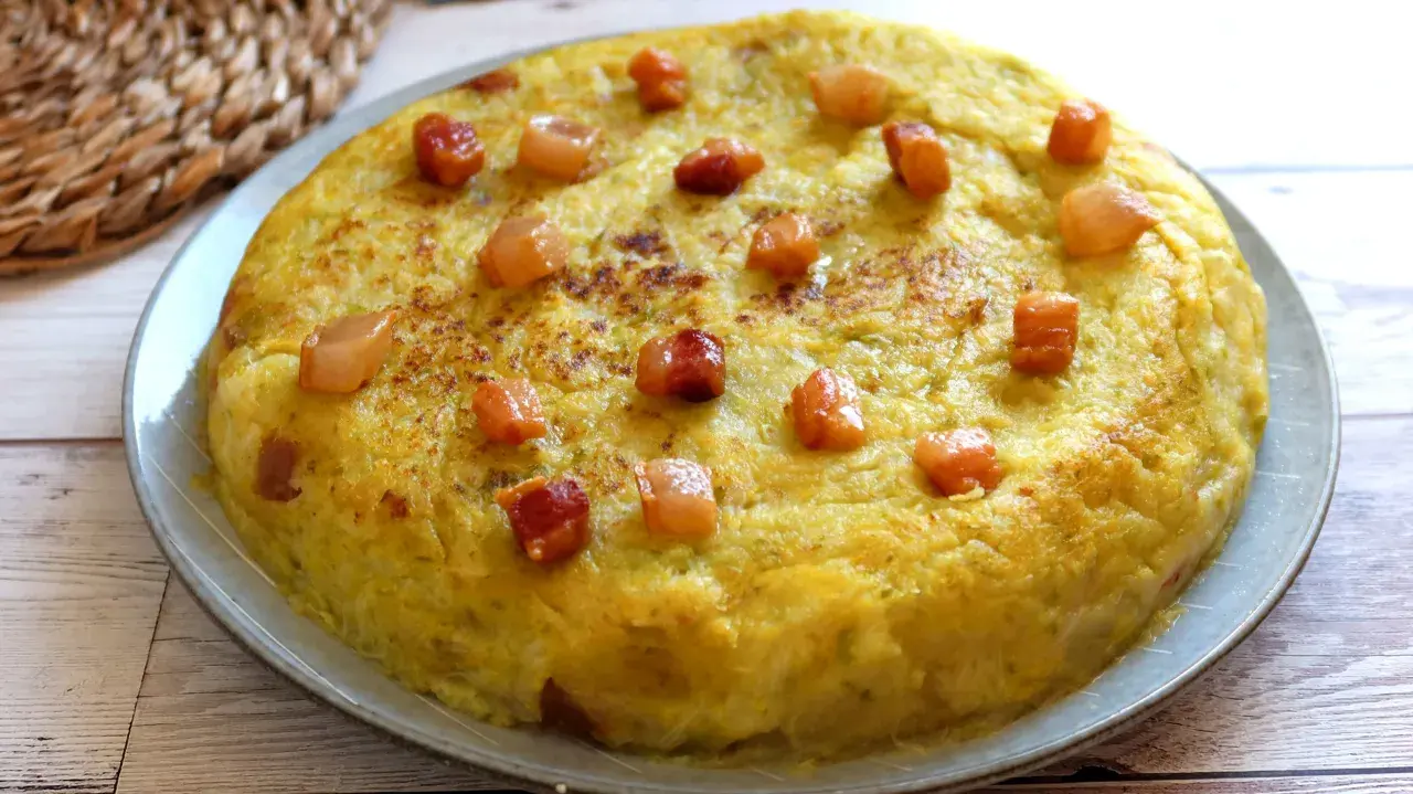 Un delicioso trinxat de la Cerdanya, una tortilla dorada con trocitos de tocino crujiente, lista para disfrutar.